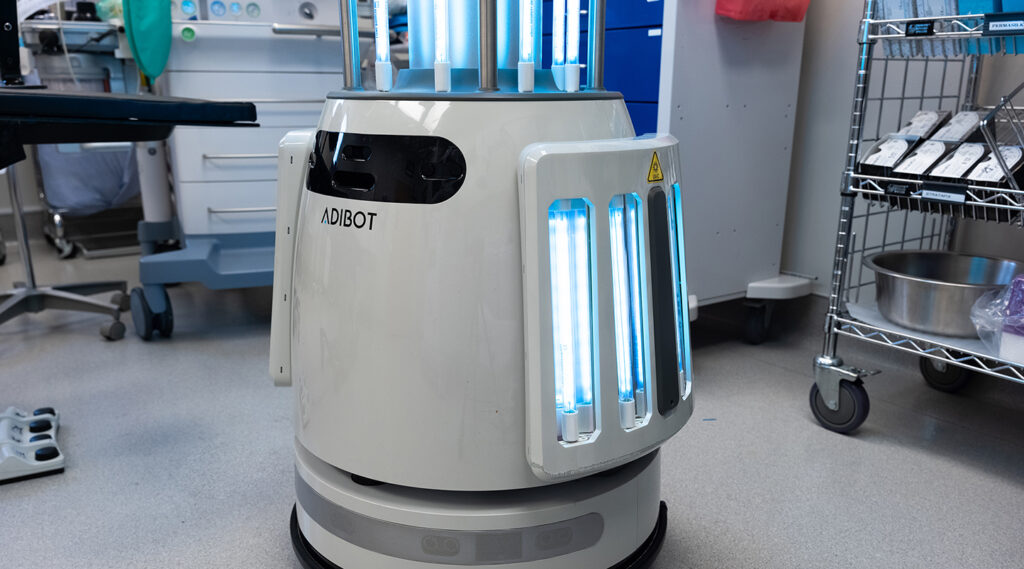 Bottom portion of the ADIBOT A1 fully autonomous UV-C disinfection robot with UV-C lamps turned on in the middle of an operating room.