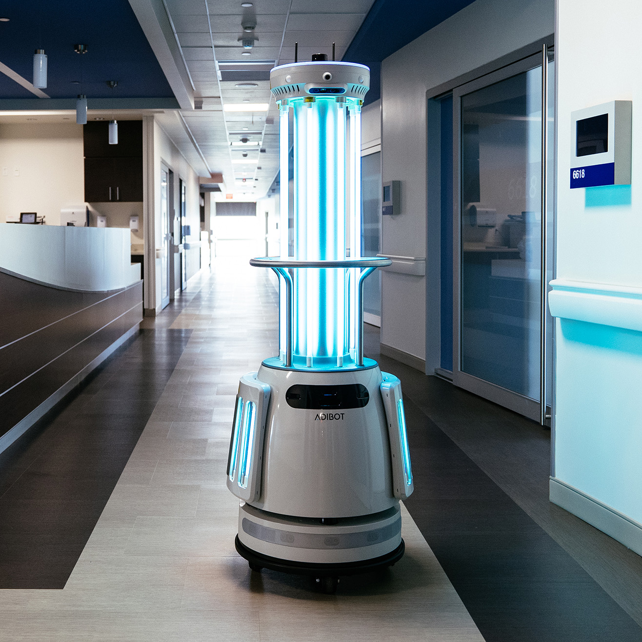 An ADIBOT A1 UV-C disinfection robot with UV-C lamps turned on in a hospital corridor.
