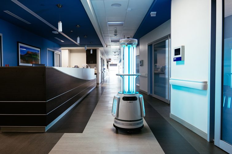 The ADIBOT A1 fully autonomous UV-C disinfection robot with UV-C lamps turned on traveling down the corridor of a hospital.