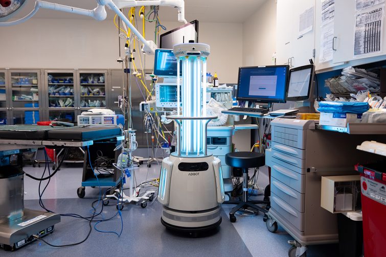 The ADIBOT A1 fully autonomous UV-C disinfection robot with UV-C lamps turned on during a disinfection session in a hospital operating room.